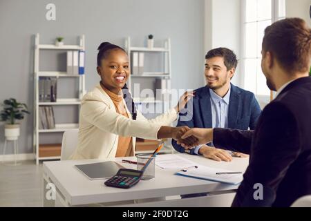 Felice giovane coppia interracial scuotere la mano di manager banca maschile broker Foto Stock