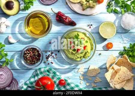 Ciotola di guacamole e ingredienti su sfondo blu. Vista dall'alto. Foto Stock