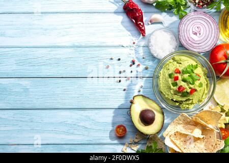 Ciotola di guacamole e nachos con ingredienti su sfondo blu. Con spazio per la copia. Vista dall'alto. Foto Stock