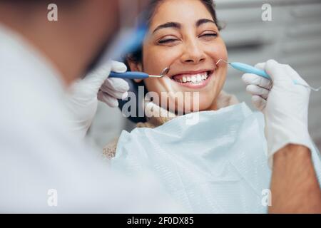 Vista sulla spalla di un dentista che esamina i denti di un paziente in clinica dentale. Femmina che ha i suoi denti esaminati da un dentista. Foto Stock