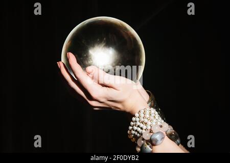 Le mani di Fortuneteller su un orb di vetro su sfondo nero. Previsione del futuro Foto Stock