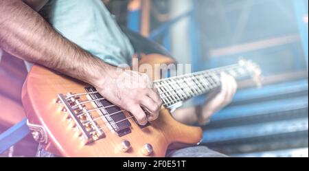 L'uomo suona la chitarra sul palco circondato dalla luce Foto Stock