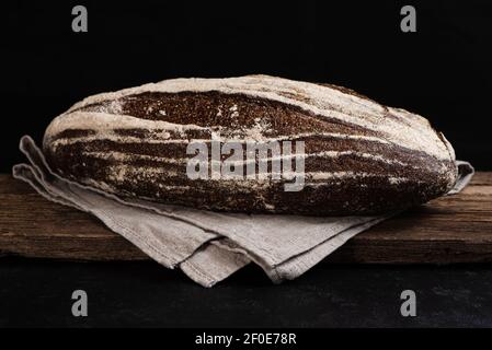 Pane di segale artigianale appena sfornato su tavola di legno. Primo piano di pane di fattoria al lievito. Tasto basso Foto Stock