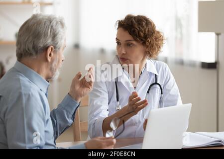 Medico femminile consultare paziente maschile maturo in clinica Foto Stock