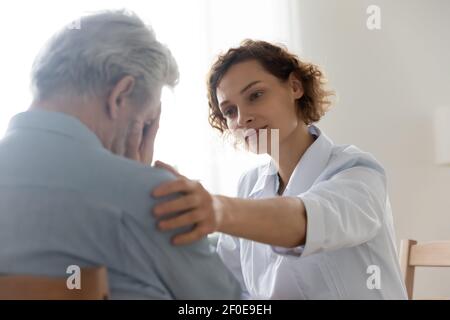 Cura giovane medico sostegno conforto malcontento paziente maturo Foto Stock