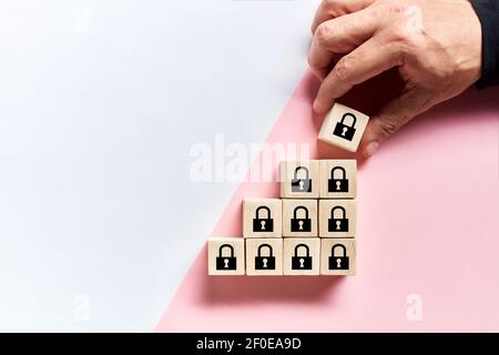 Mano maschio che dispone i cubi di legno con le icone di blocco di sicurezza. Aumento del concetto di sicurezza o precauzioni di sicurezza. Foto Stock