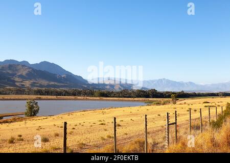 Vista panoramica di una diga di fattoria e le montagne tra Villersdorp e Worcester al tramonto, Overberg, Capo Occidentale, Sud Africa Foto Stock