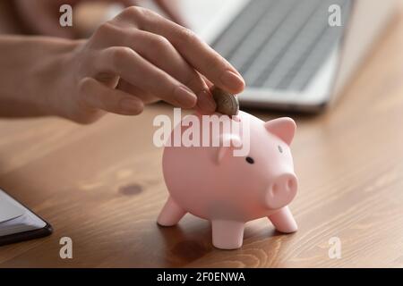 Primo piano di donna messo moneta in piggybank Foto Stock
