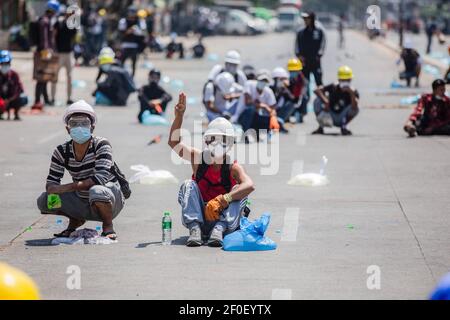 Un manifestante pacifico fa il saluto a tre dita verso la polizia antisommossa durante una protesta contro il colpo di stato militare.la polizia di Myanmar ha attaccato i dimostranti con proiettili di gomma, munizioni vive, gas lacrimogeni e bombe stordite in risposta ai dimostranti anti anti militari del colpo di stato la domenica. Un totale di 1758 persone sono state perseguitate, di cui 1440 ancora nelle prigioni militari del Myanmar e 60 sono state uccise dall'inizio delle proteste contro il colpo di Stato militare. L'esercito del Myanmar ha arrestato il consigliere di Stato del Myanmar Aung San Suu Kyi il 01 febbraio 2021 e ha dichiarato uno stato di emergenza mentre cogliendo il potere i Foto Stock