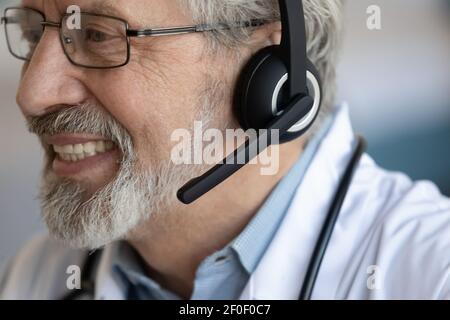 Primo piano di sorridente medico maschile maturo in cuffie Foto Stock