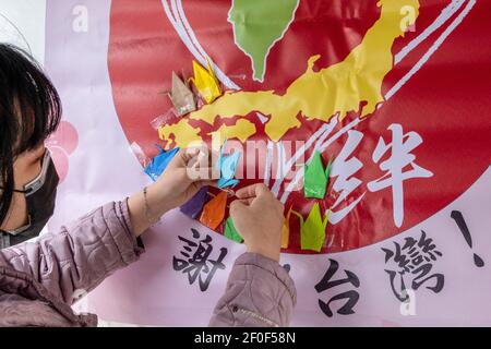 New Taipei, Taiwan. 07 marzo 2021. Un membro del 'Comitato Arigatou Taiwan' mette su una parete gru di carta origami durante la cerimonia di inaugurazione di un monumento che rappresenta i legami amichevoli dei paesi. Quest'anno è il decimo anniversario del terremoto del Giappone dell'Est 311. Nel 2011, il governo e il settore privato di Taiwan hanno donato 25 miliardi di yen (quasi 240 milioni di dollari, la maggior parte del mondo) e inviato squadre di salvataggio in Giappone. Credit: SOPA Images Limited/Alamy Live News Foto Stock