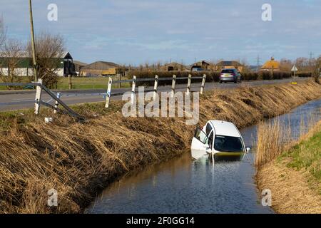 Rye, Sussex orientale, Regno Unito. 7 Mar 2021. L'auto White Hyundai i10 si schiantò attraverso la barriera di recinzione in legno e finì per metà sommersa in una fossa d'acqua che corre parallela alla strada principale A259 tra Rye, East Sussex e Ashford, Kent. Photo Credit: Paul Lawrenson /Alamy Live News Foto Stock