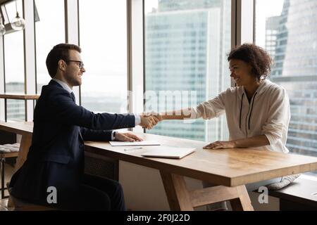 Vista laterale sorridente hr manager scuotendo la mano di donna afroamericana Foto Stock