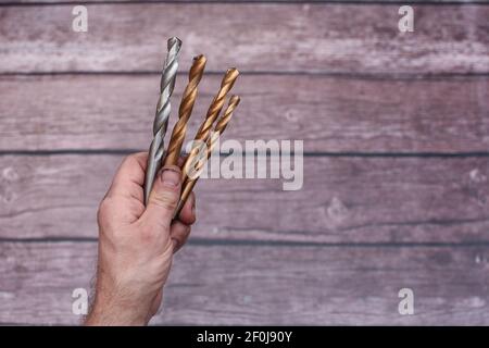 punte da trapano ravvicinate in mano. La mano strisciata di un lavoratore con punte da trapano. Caratteri Foto Stock