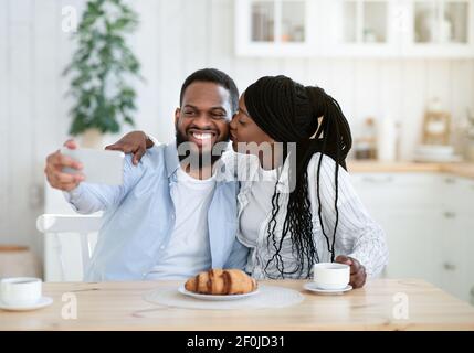 Tempo selfie. Allegro Black Guy scattare foto con la sua ragazza in cucina Foto Stock