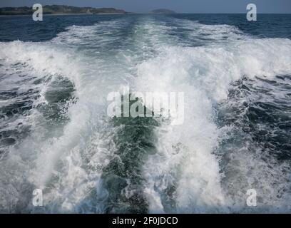 Svegliati da un motoscafo che naviga lungo lo stretto menai ad anglesey. Puffin isola e la costa con mare blu e un cielo estivo. Foto Stock