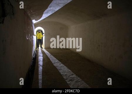 Donna con faro in piedi nello storico sistema sotterraneo italiano di Unska Kolisevka, Slovenia Foto Stock