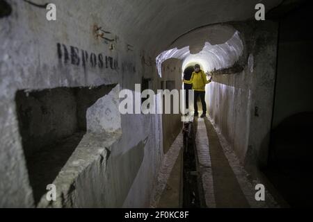 Donna con faro in piedi nello storico sistema sotterraneo italiano di Unska Kolisevka, Slovenia Foto Stock