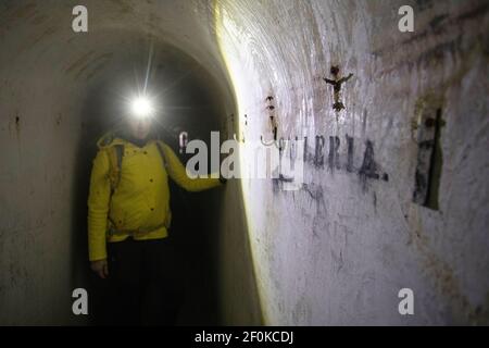 Donna con faro in piedi nello storico sistema sotterraneo italiano di Unska Kolisevka, Slovenia Foto Stock