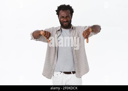 Cattiva idea, il ragazzo la disapprova. Riluttante e giudicante deluso afroamericano uomo bearned con afro hairstyle, cringe da dislike, mostrando Foto Stock