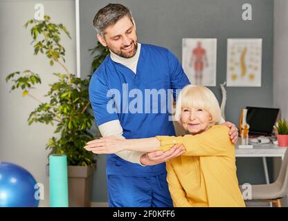 Donna anziana con lesione ad un giunto a gomito. Dolore articolare. Il fisioterapista tiene la mano di una donna durante la riabilitazione Foto Stock