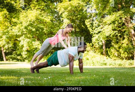 Una coppia mista che fa pushup di fitness nel parco Foto Stock