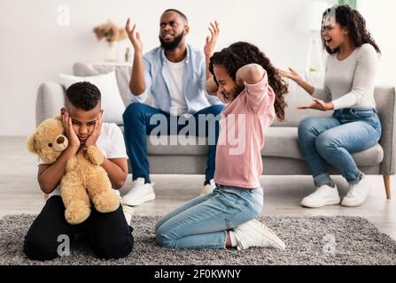 Bambini tristi con i loro genitori combattenti sullo sfondo Foto Stock