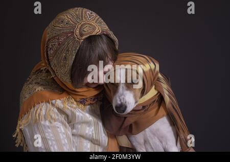 Bel ritratto basso chiave di donna caucasica matura con bella cane basenji entrambi indossando copricapo Foto Stock