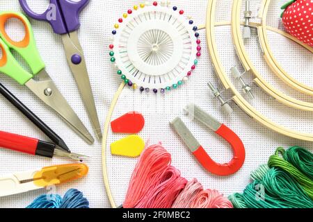 Cerchio per ricamo, ago e filo di diverso colore per cucire adagiato su  fondo bianco. Impostare per la vista dall'alto dell'ago Foto stock - Alamy