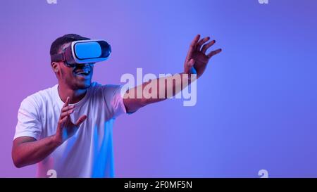 Esperienza virtuale. Eccitato African Man indossare visore VR, giocando videogioco Foto Stock