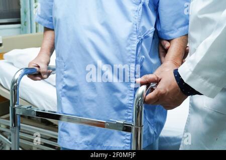 Il medico aiuta e cura Asian anziano o anziano donna anziana usa il camminatore con salute forte mentre cammina. Foto Stock