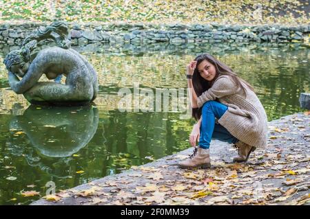 Ragazza di bellezza seduta vicino allo stagno Foto Stock