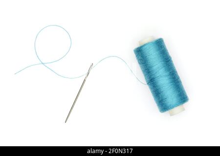 Concetto di cucitura: Bobina di filo blu con filo passante attraverso l'ago, tagliata e isolata su sfondo bianco. Foto Stock