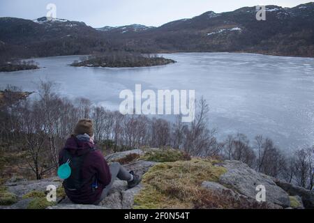 Escursionista con Samoyed Husky cane ​​looking al lago congelato e. fiordo di Rogaland Norvegia Foto Stock