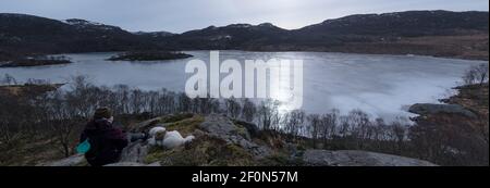 Escursionista con Samoyed Husky cane ​​looking al lago congelato e. fiordo di Rogaland Norvegia Foto Stock