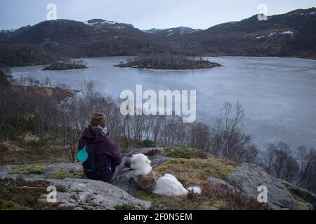 Escursionista con Samoyed Husky cane ​​looking al lago congelato e. fiordo di Rogaland Norvegia Foto Stock