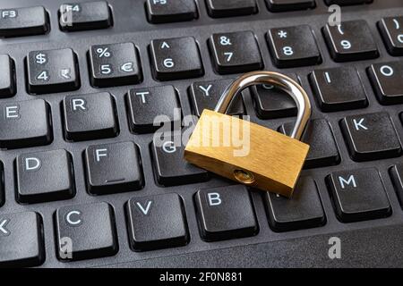 Lucchetto metallico su una tastiera nera del computer. Blocco chiuso su una tastiera desktop. Protezione del computer e di Internet, per salvare i concetti di dati riservati. Vista dall'alto Foto Stock