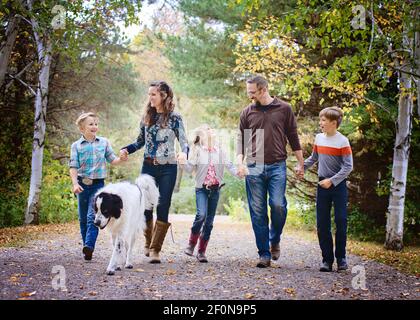 Famiglia felice di cinque camminando lungo la strada di campagna con il cane grande. Foto Stock