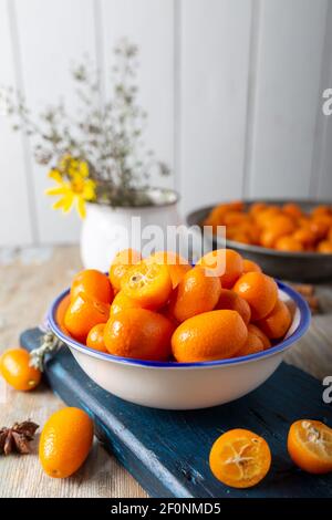 Kumquat freschi maturi in ciotola su tavolo di legno. Foto Stock