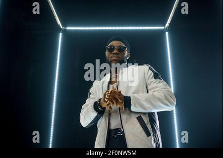 Elegante rapper in occhiali da sole, sfondo scuro Foto Stock