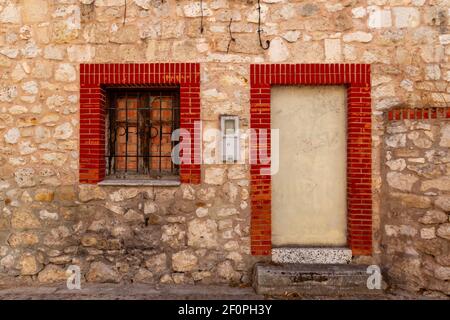 Particolare di un vecchio muro di pietra con una porta cancellata e finestra Foto Stock