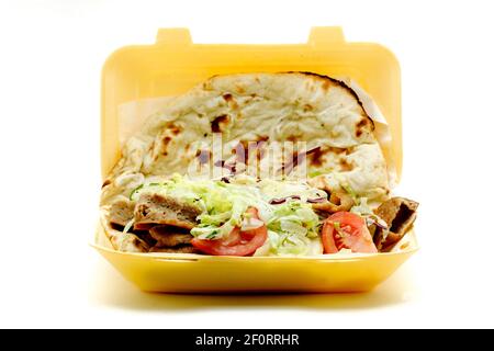 Un doner Kebab da asporto, o kebab donatore, servito con insalata e avvolto in un pane Nan. Il kebab è stato venduto in un contenitore monouso in polistirene. Foto Stock