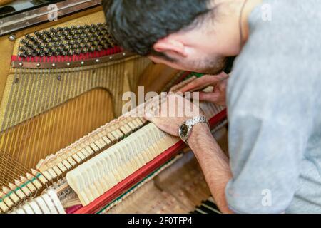 Processo di sintonizzazione del pianoforte. Primo piano della mano e strumenti di sintonizzazione che lavorano al pianoforte a coda. Vista dettagliata di piano verticale durante una sintonizzazione Foto Stock