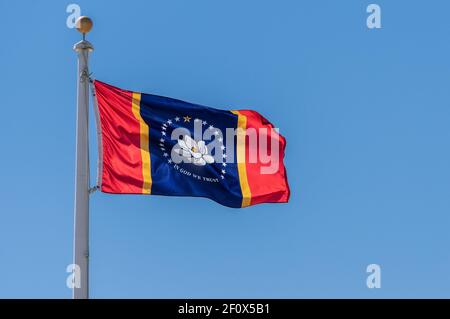 Bandiera dello stato del New Mississippi che oscilla nel vento contro una cielo blu Foto Stock