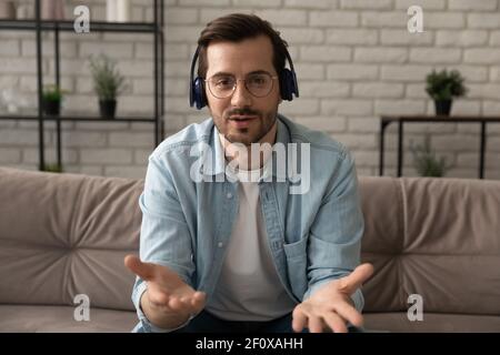 Un tutor uomo che indossa cuffie e auricolari sicuro da millenni ti darà una lezione a distanza Foto Stock