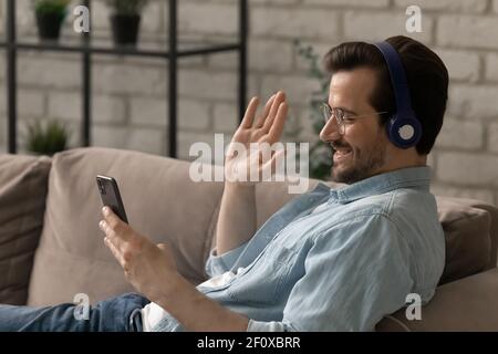 Sorridente ragazzo salutare amico wave mano ciao chiamando al telefono Foto Stock