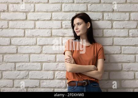 Ambiziosa giovane donna stand by muro croce braccia guardare via Foto Stock