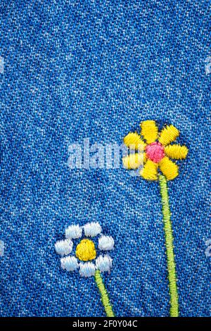 Fiori ricamati su un frammento di tessuto jeans denim blu Foto Stock