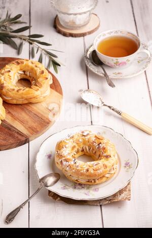 Piccola pasticceria Paris Brest in un vecchio piatto su a. tavolo di legno bianco Foto Stock