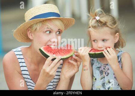 Madre e figlia godendo delle fette di cocomero Foto Stock